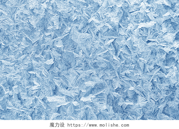 蓝色的霜块特写镜头在冬天的霜在窗户玻璃上的图案。磨砂玻璃纹理。蓝色